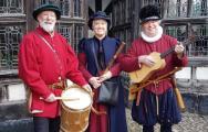 3 people in tudor costume holding instruments